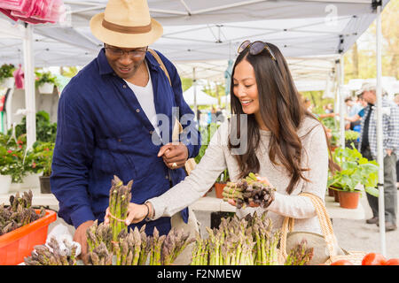 Couple shopping for asparagus in farmers market Stock Photo