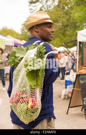 African American man carrying bag of produce at market Stock Photo