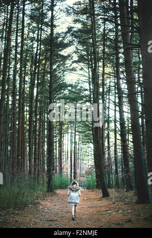 Caucasian woman walking on dirt path in forest Stock Photo