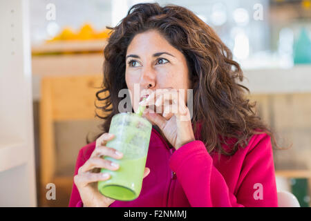 Hispanic woman drinking green juice Stock Photo