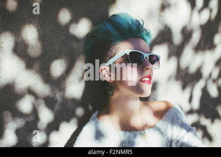 Stylish Caucasian woman wearing sunglasses in shade Stock Photo