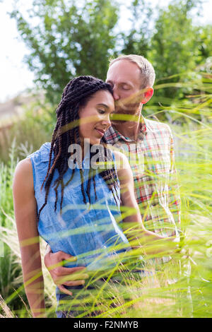 Couple kissing in tall grass in garden Stock Photo