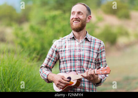 Caucasian man playing ukulele outdoors Stock Photo