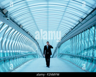 Caucasian businessman talking on cell phone in tunnel Stock Photo