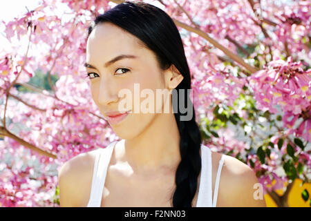 Mixed race woman standing under flowering tree Stock Photo