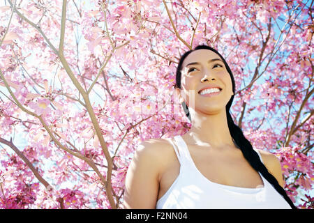 Mixed race woman standing under flowering tree Stock Photo
