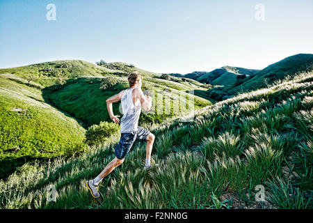 Caucasian athlete running on rural hills Stock Photo