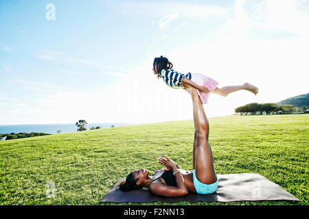 Mother holding daughter with legs in park Stock Photo