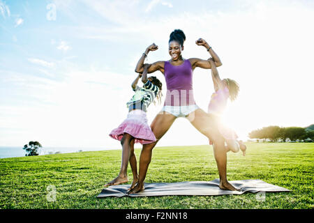 Woman lifting children with biceps in park Stock Photo