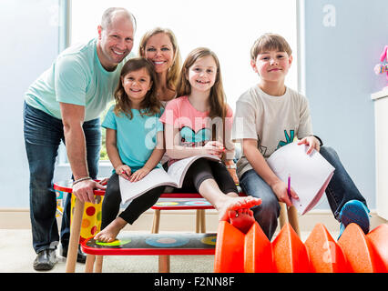 Caucasian family smiling at table in playroom Stock Photo