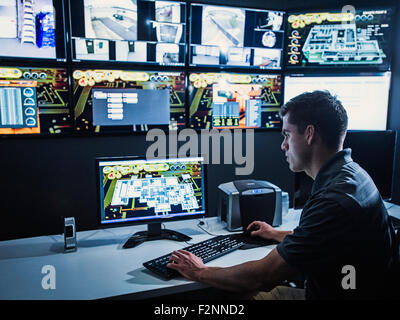 Hispanic security guard watching monitors in control room Stock Photo