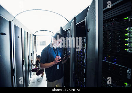 Technician using digital tablet in server room Stock Photo