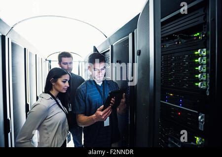 Technicians using digital tablet in server room Stock Photo