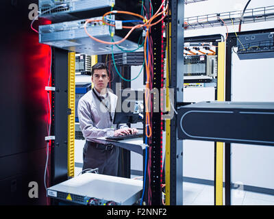 Hispanic technician using computer in server room Stock Photo