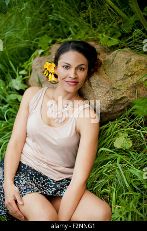 Mixed race woman laying on rock in tall grass Stock Photo