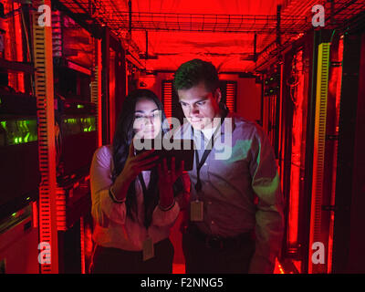 Technicians using digital tablet in server room Stock Photo