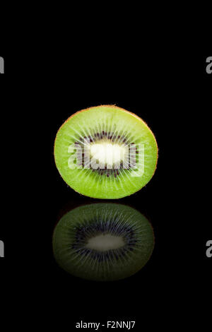 A cut kiwi on a black reflective background. Stock Photo