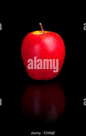 A red apple on a black reflective background. Stock Photo