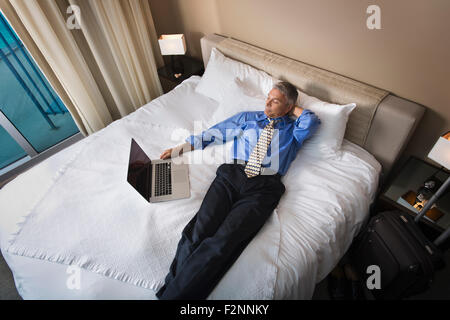 Caucasian businessman using laptop on hotel bed Stock Photo