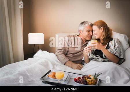 Smiling couple having breakfast in bed Stock Photo