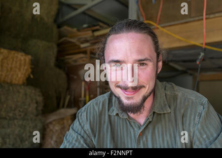Caucasian farmers smiling in barn Stock Photo