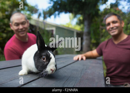 Mixed race men with rabbit on picnic table Stock Photo