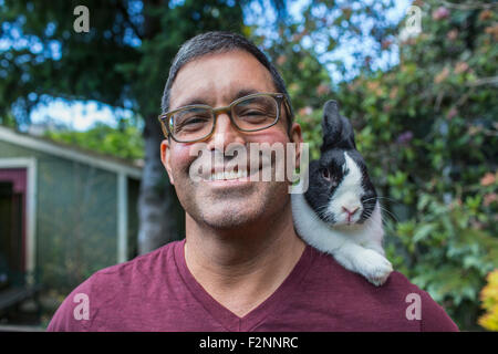 Mixed race man carrying rabbit on shoulder Stock Photo