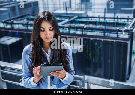Mixed race businesswoman using digital tablet on balcony over server room Stock Photo