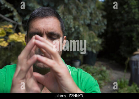 Mixed race man concentrating with hands clasped Stock Photo