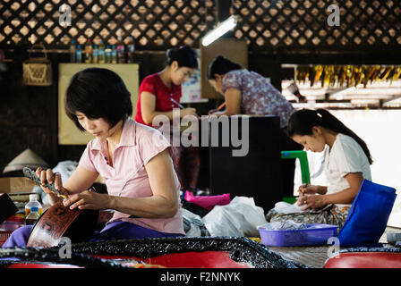Asian artisans carving traditional designs in workshop Stock Photo