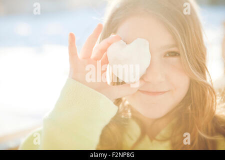 Caucasian girl covering eye with heart shape Stock Photo