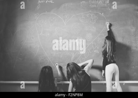 Caucasian girls drawing on classroom chalkboard Stock Photo