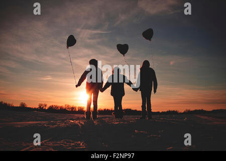 Caucasian girls walking with balloons at sunset Stock Photo