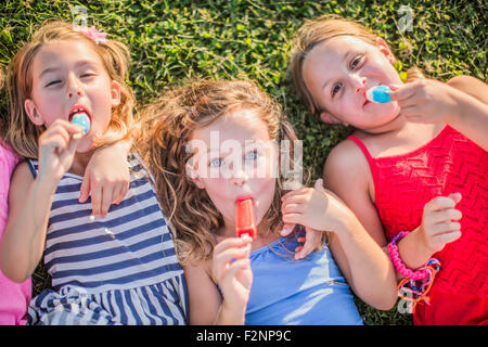 Girls eating flavored ice in grass Stock Photo