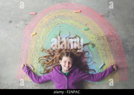 Caucasian girl laying on chalk rainbow Stock Photo