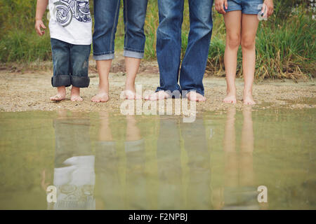 Family wearing jeans at still puddle Stock Photo