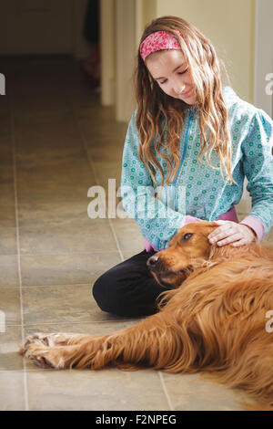 Caucasian girl petting dog on floor Stock Photo