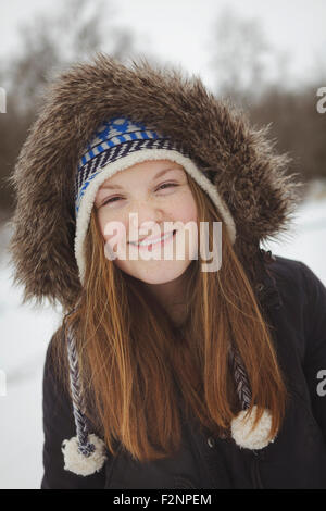 Caucasian teenage girl wearing fur coat and hat in snow Stock Photo