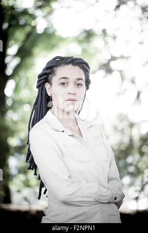 Serious woman with dreadlocks standing outdoors Stock Photo