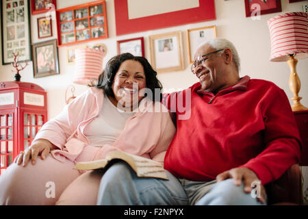 Couple reading book in living room Stock Photo