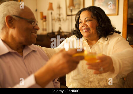 Couple toasting each other with wine in living room Stock Photo