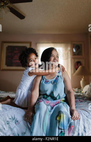Grandmother and granddaughter hugging on bed Stock Photo
