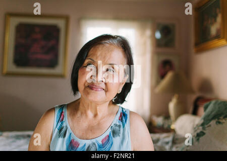 Smiling older woman sitting on bed Stock Photo