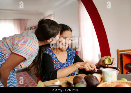 Woman kissing grandmother cooking in kitchen Stock Photo