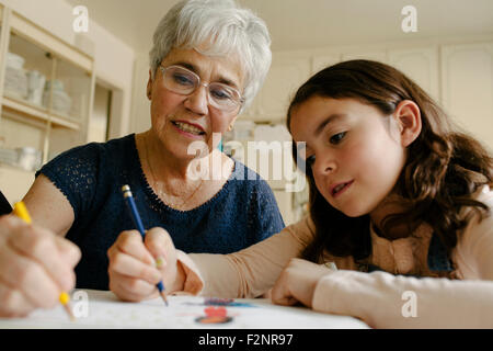 Grandmother and granddaughter drawing at table Stock Photo