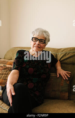Older woman sitting on sofa Stock Photo
