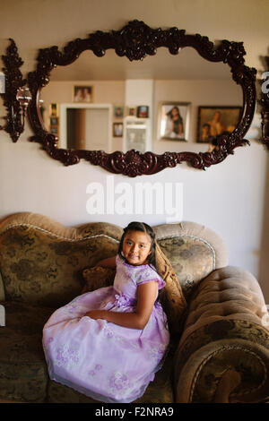 Hispanic girl sitting on living room sofa Stock Photo
