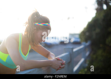 Close up of woman leaning over fence in parking lot Stock Photo