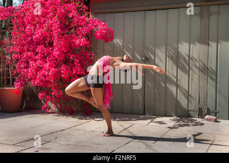 Woman practicing yoga near flowers and fence Stock Photo