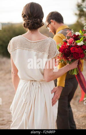 Bride and groom walking on rural hilltop Stock Photo